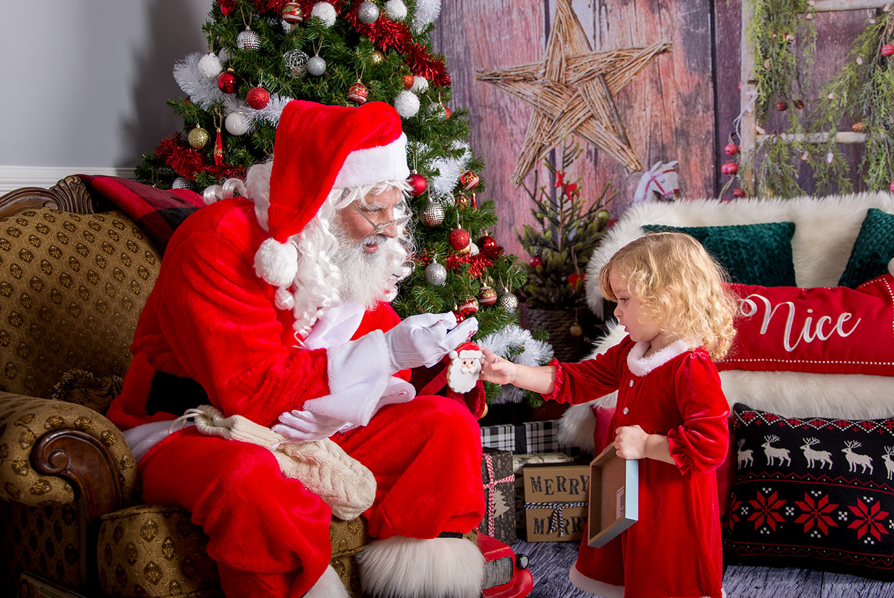 A-Girl-in-a-Red-Festive-Dress-Receives-a-Santa-Christmas-Ornament-from-Kris-Kringle-Himself