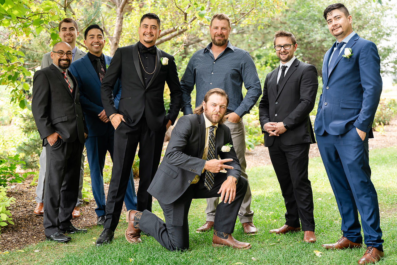Best friends posing with a proud groom during a photoshoot in a forest setting.