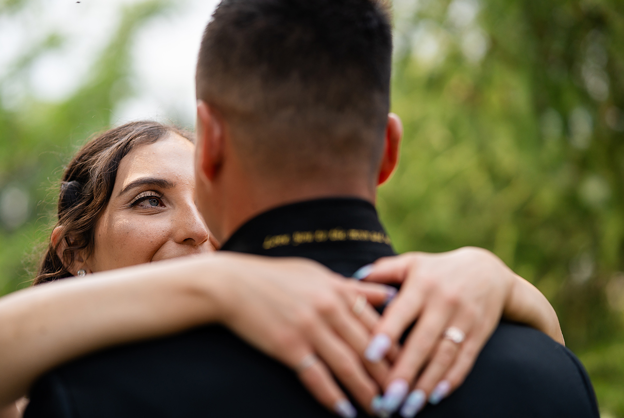 Bride with her arms wrapped around her groom's shoulders, gazing lovingly at her new husband with her eyes in focus during their wedding ceremony.