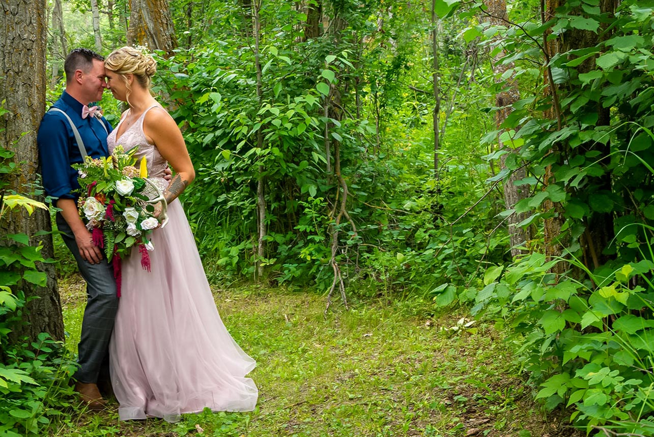 Bride and groom walking arm in arm through pine forest trail