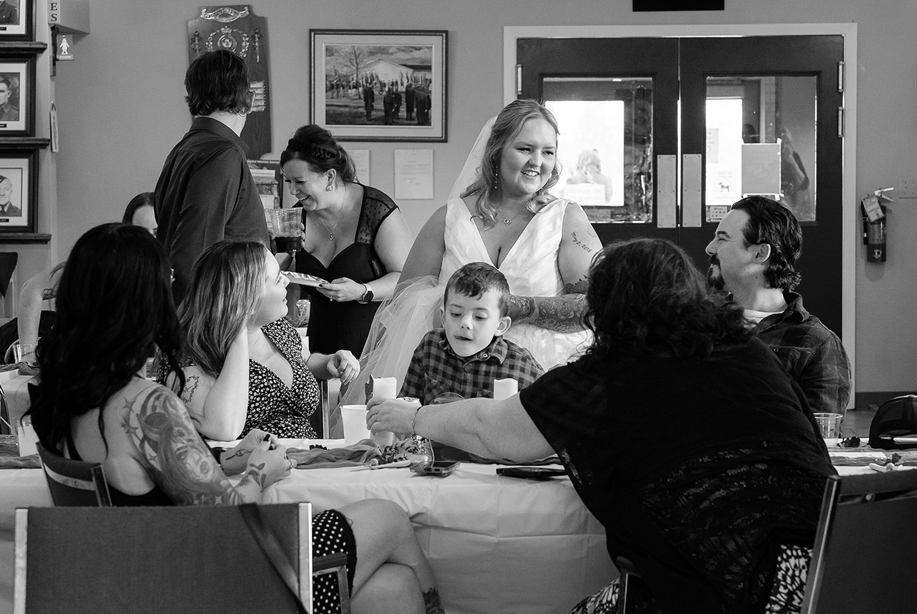Bride smiles while greeting guests around the tables during the wedding reception at the Royal Canadian Legion