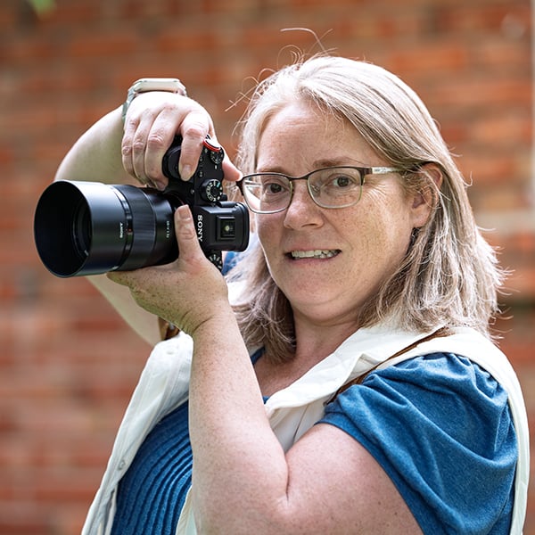 Catriona Hope holding her Sony camera, smiling during an outdoor portrait session in Sherwood Park