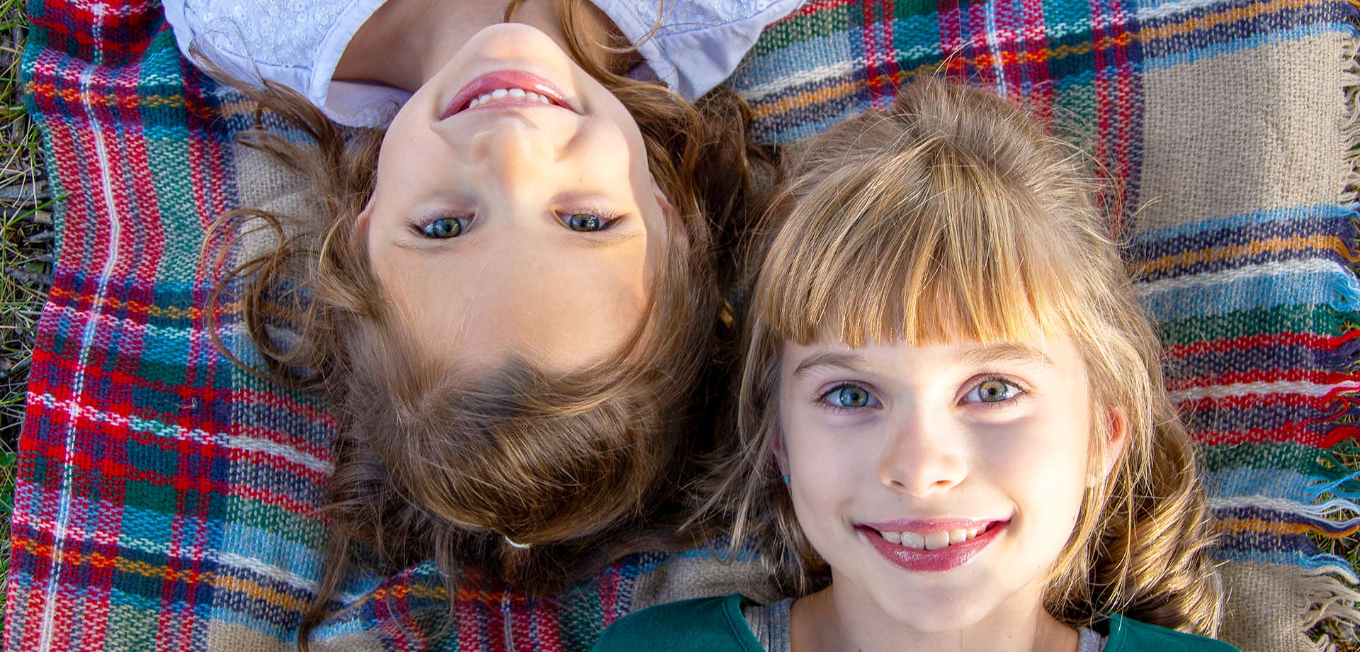 Two sisters laying on a picnic blanket surrounded by flowers at Centennial Park in Sherwood Park