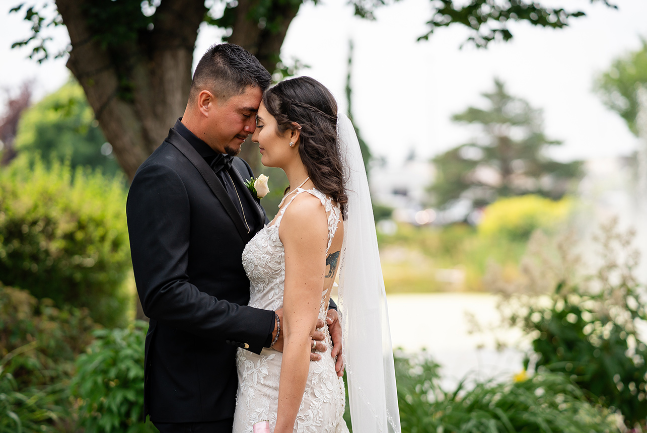 A couple's intimate moment with foreheads touching and the groom lovingly holding the bride's hips, exuding a tranquil feeling.