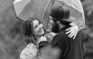 Brylie and Rylie share a laugh under an umbrella during their rainy Edmonton engagement session