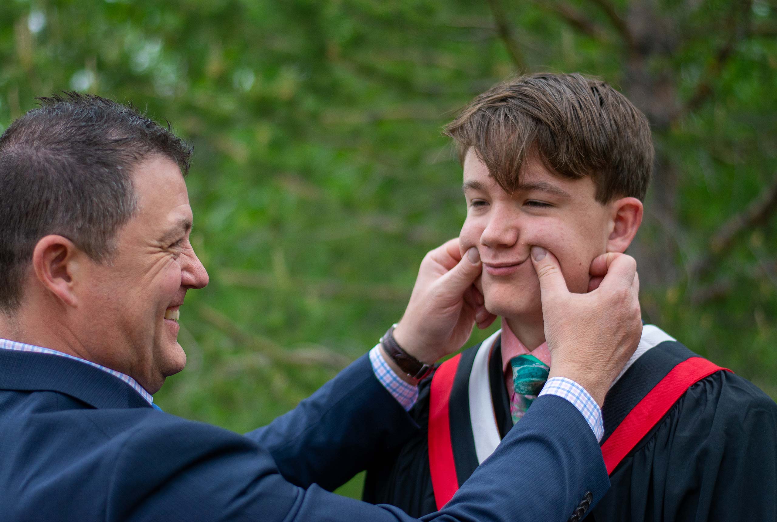 Dad squeezes sons face for camera smile