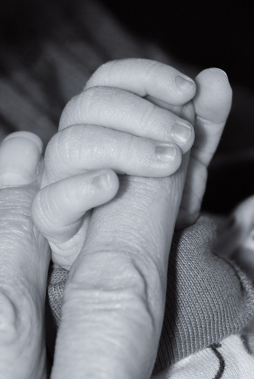 A precious moment captured in monochrome. A newborn baby tightly holds onto her mother's finger, showcasing the beautiful bond between parent and child.
