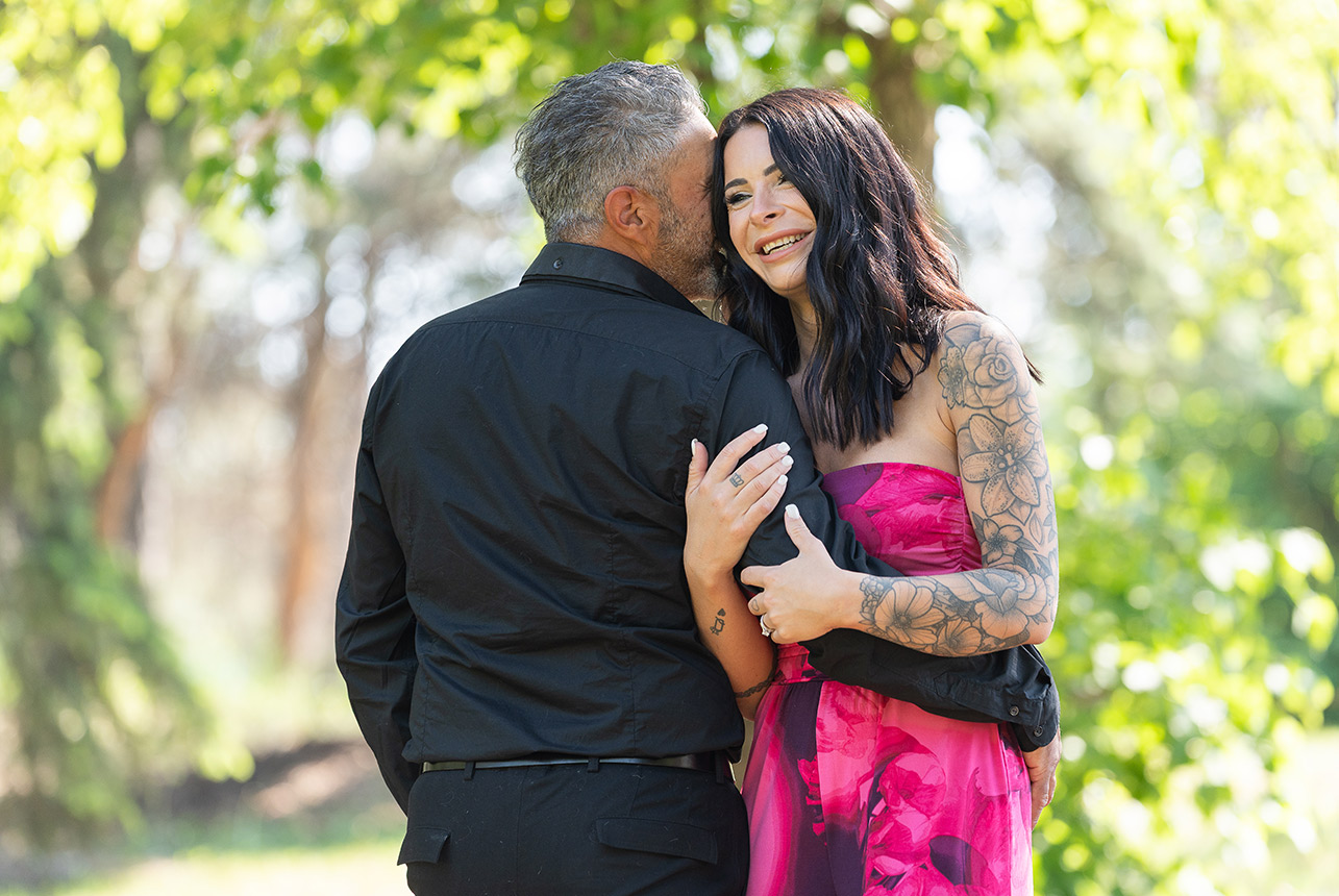Groom whispers to fiancée as she laughs in an Edmonton park
