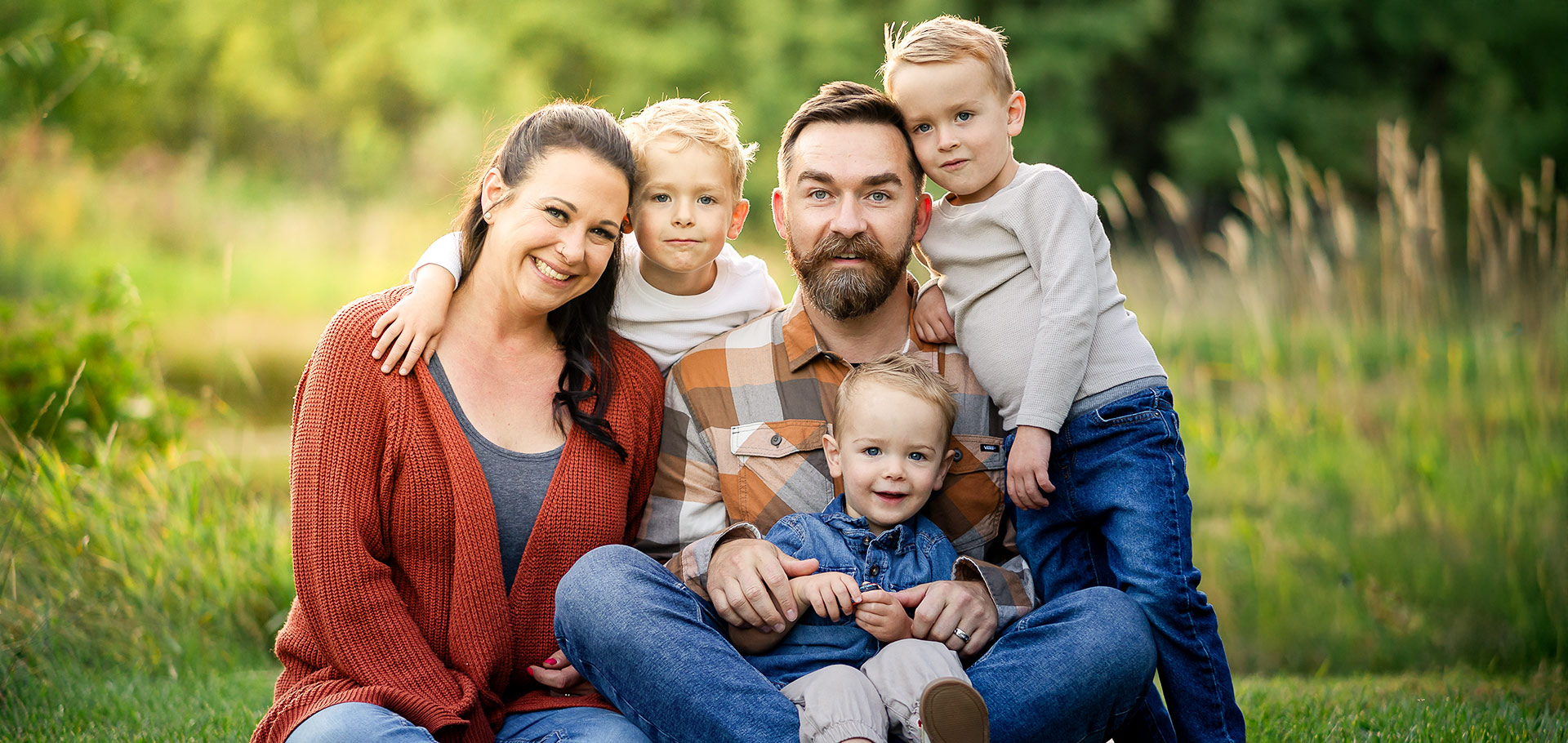Smiling family of five with three young sons at a golden‑hour photo session in Sherwood Park, Edmonton