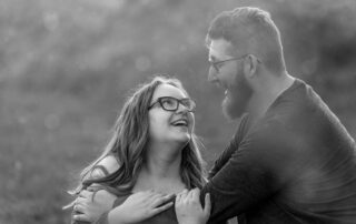 Close-up of couple smiling through soft golden light and spring haze during their Edmonton engagement session