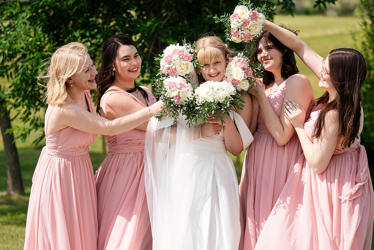erin-eric-bride-bouquet-fun Bride surrounded by bridesmaids holding floral bouquets