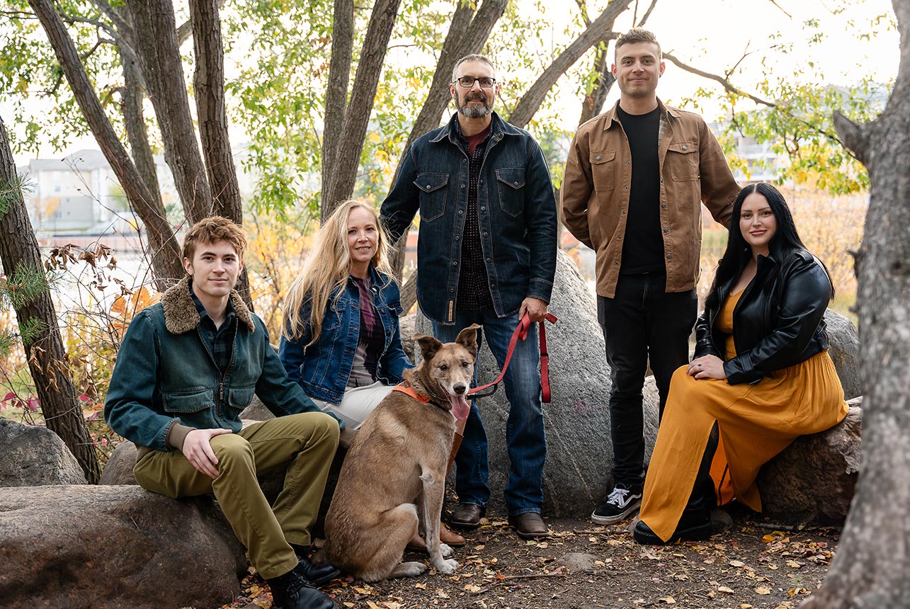 Family of five with dog posing among autumn trees on a forest path in Sherwood Park