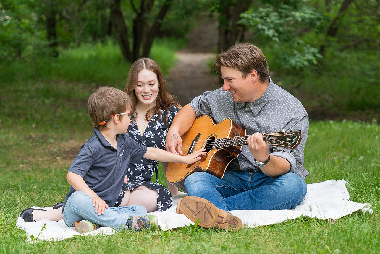 Family playing guitar near Fort Edmonton Footbridge