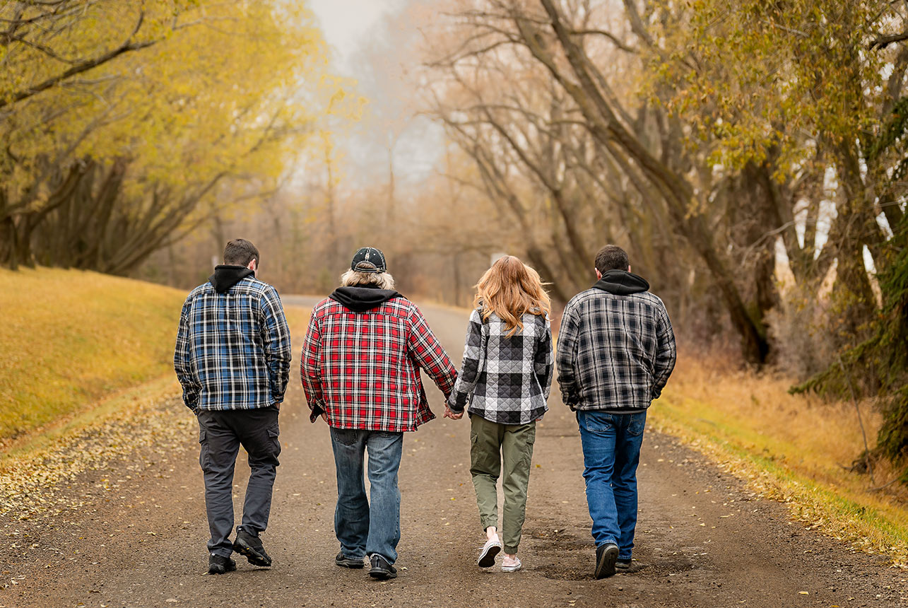 Family walking hand in hand down a country road in Alberta during autumn