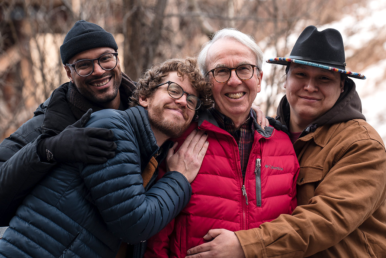 Father with three sons in winter gear at Mill Creek Ravine, Edmonton, during a family photo session.