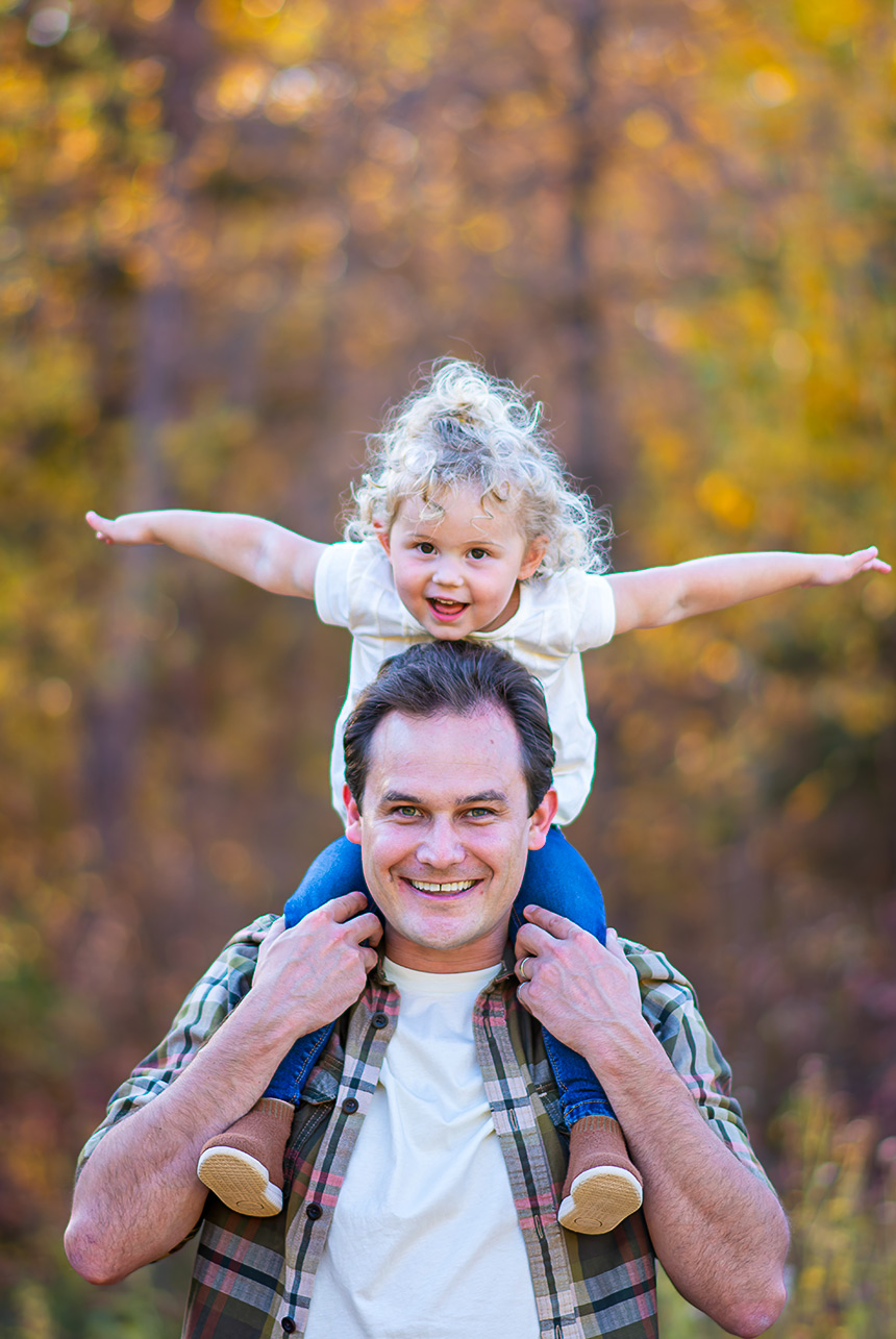 Father giving toddler a shoulder ride during an autumn family session in Sherwood Park
