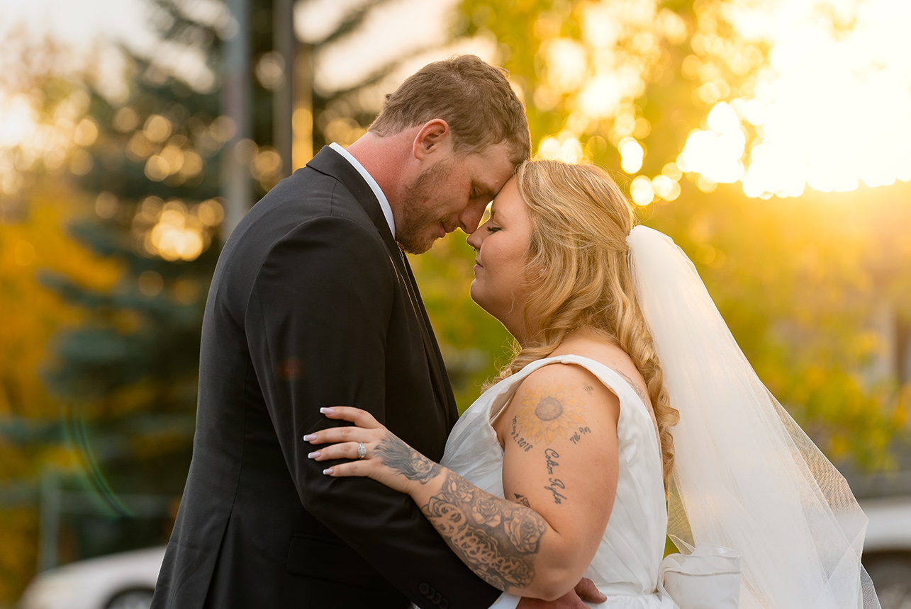 Bride and groom embracing at sunset during their outdoor wedding