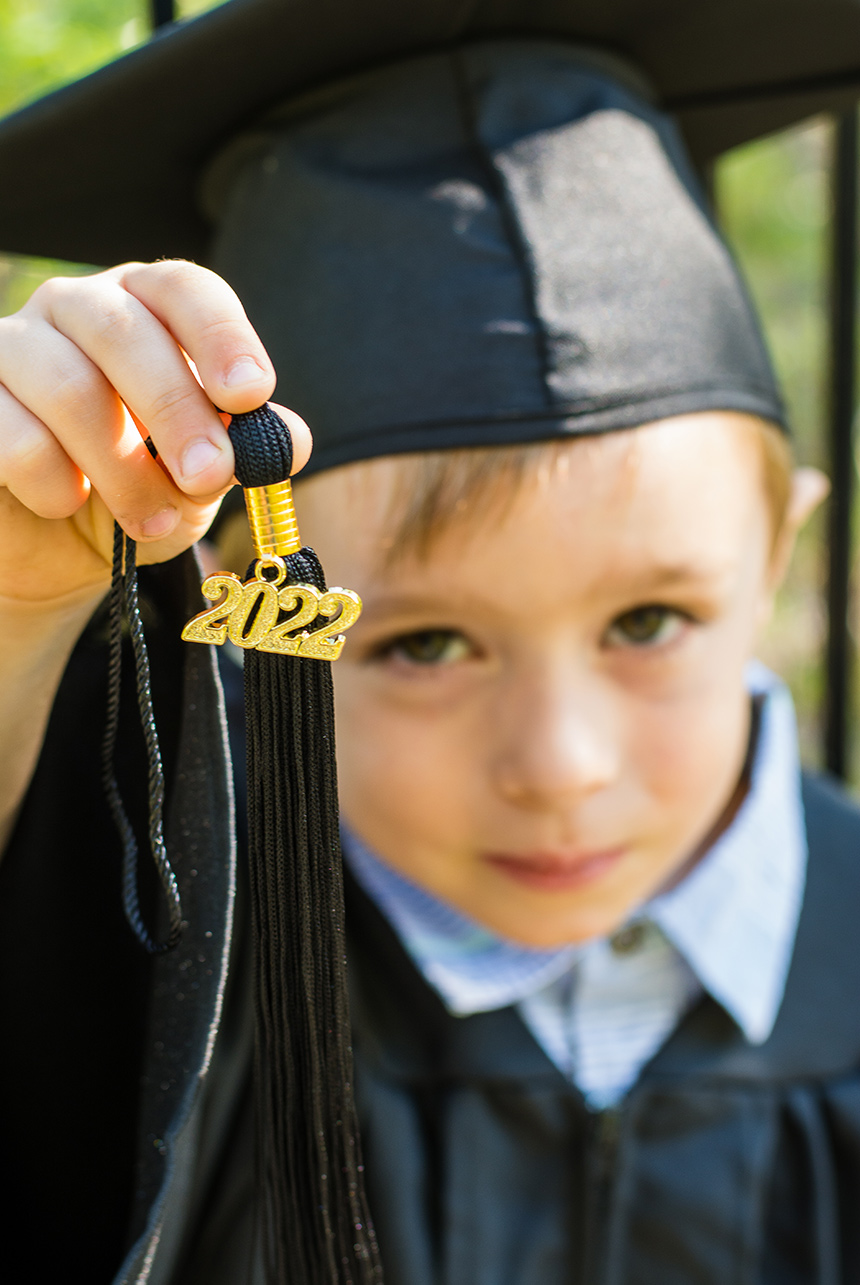 Cute handsome boy graduate from kindergarten 2022 tassel boy with cap and gown