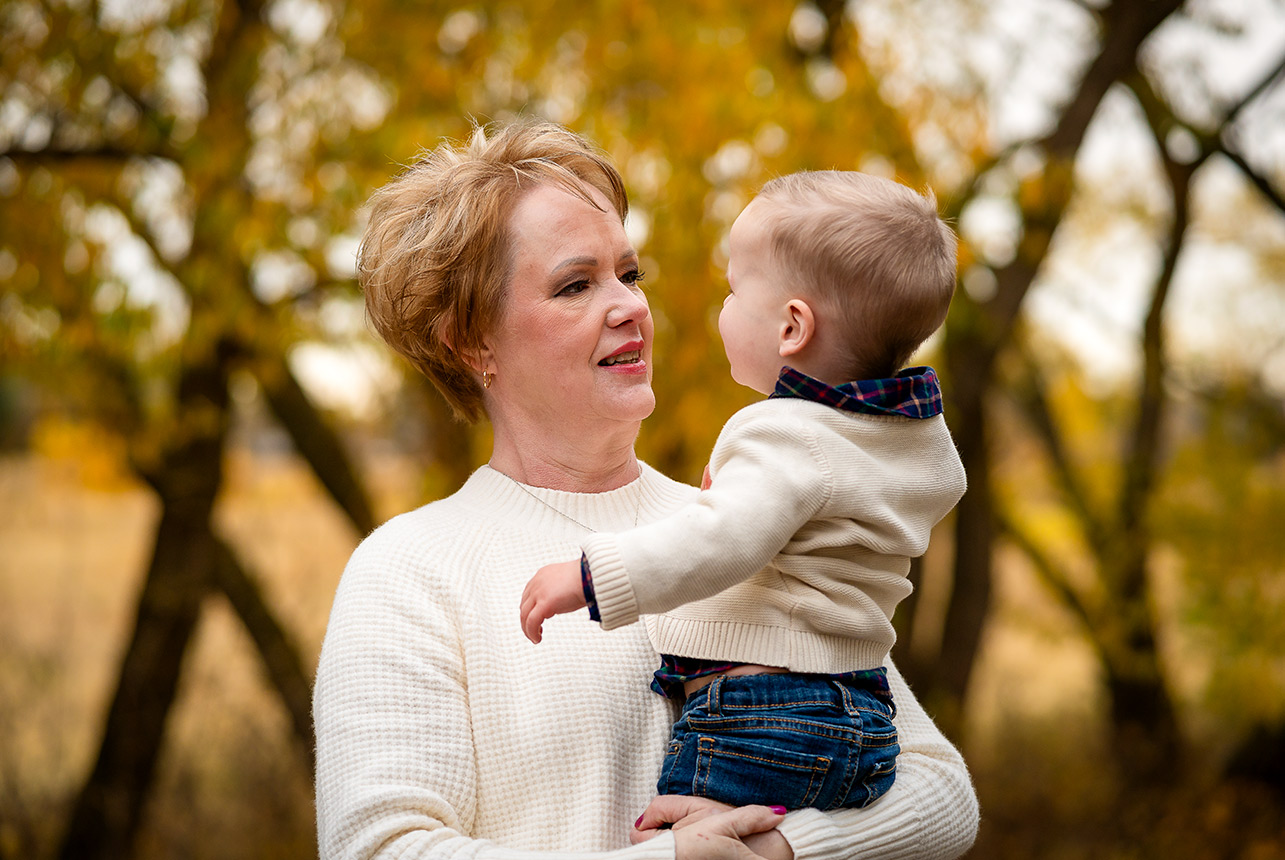 Grandmother holding her baby grandson in an autumn park in Edmonton