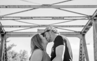 Couple sharing a kiss on an old steel bridge near Redwater, Alberta, bathed in timeless black and white