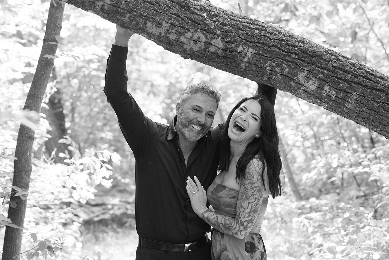Couple laughing under tree branch in Edmonton’s forested park