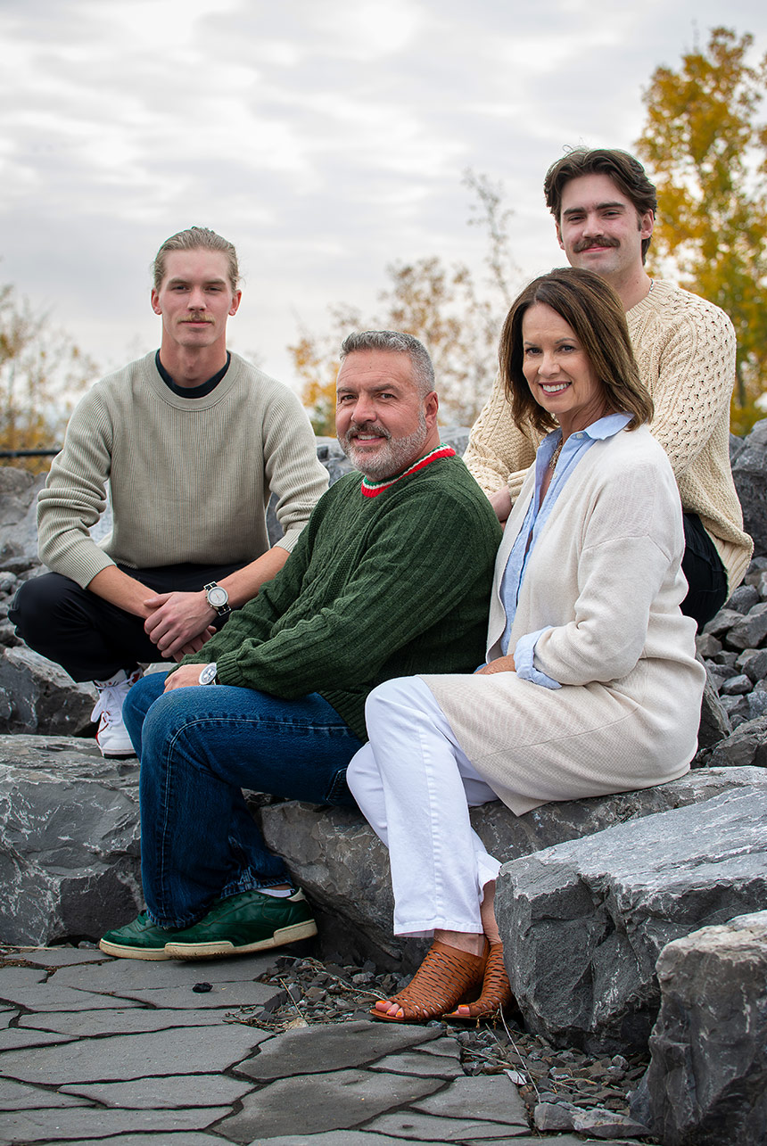 A mature family sitting staggered on boulders in an autumn setting, surrounded by fall colors.