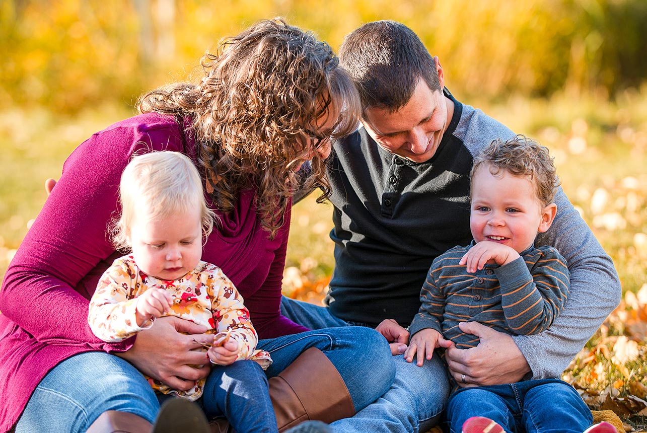Parents sitting with toddler and baby during an autumn family session in Edmonton