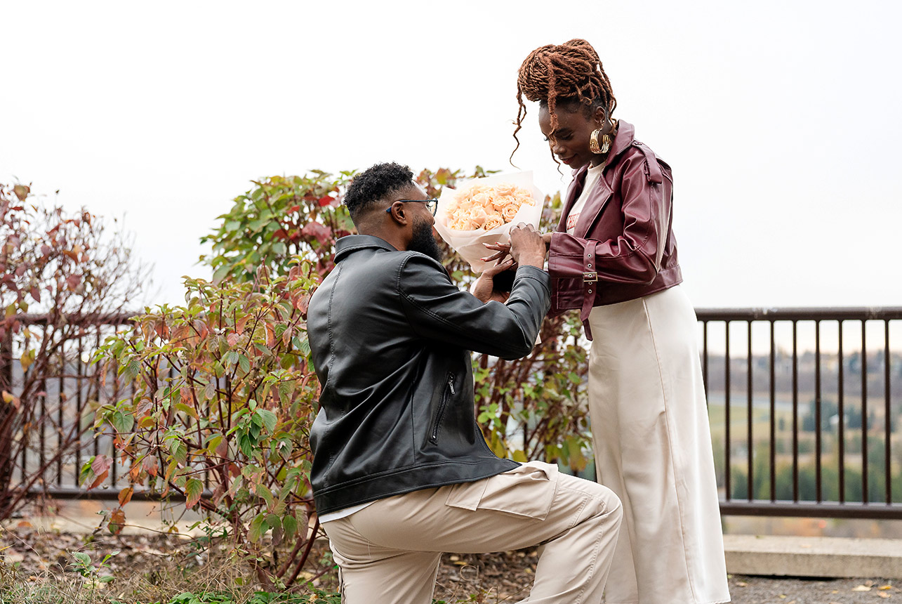 Man kneeling with bouquet proposing to woman during an autumn moment outdoors in Edmonton