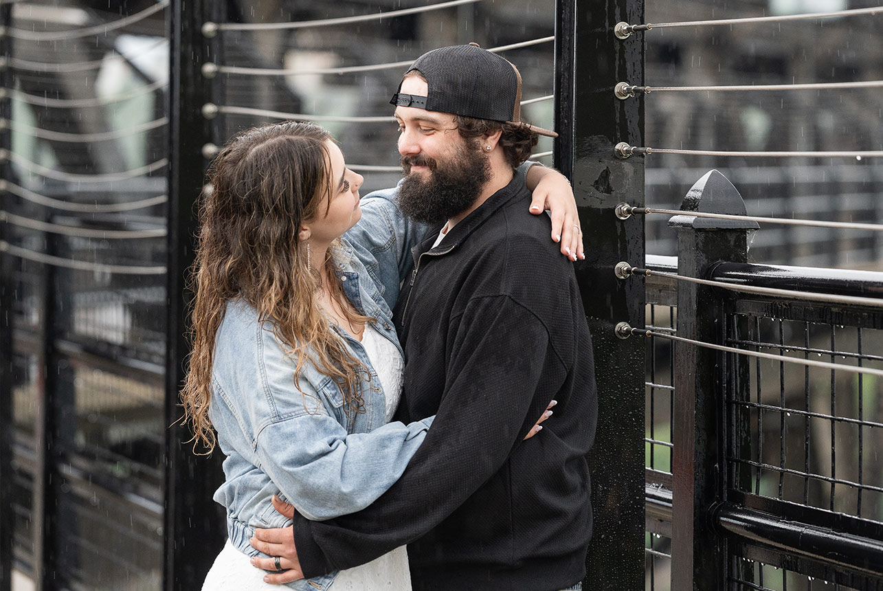 Couple embraces on Edmonton’s High Level Bridge during a soft evening rainfall