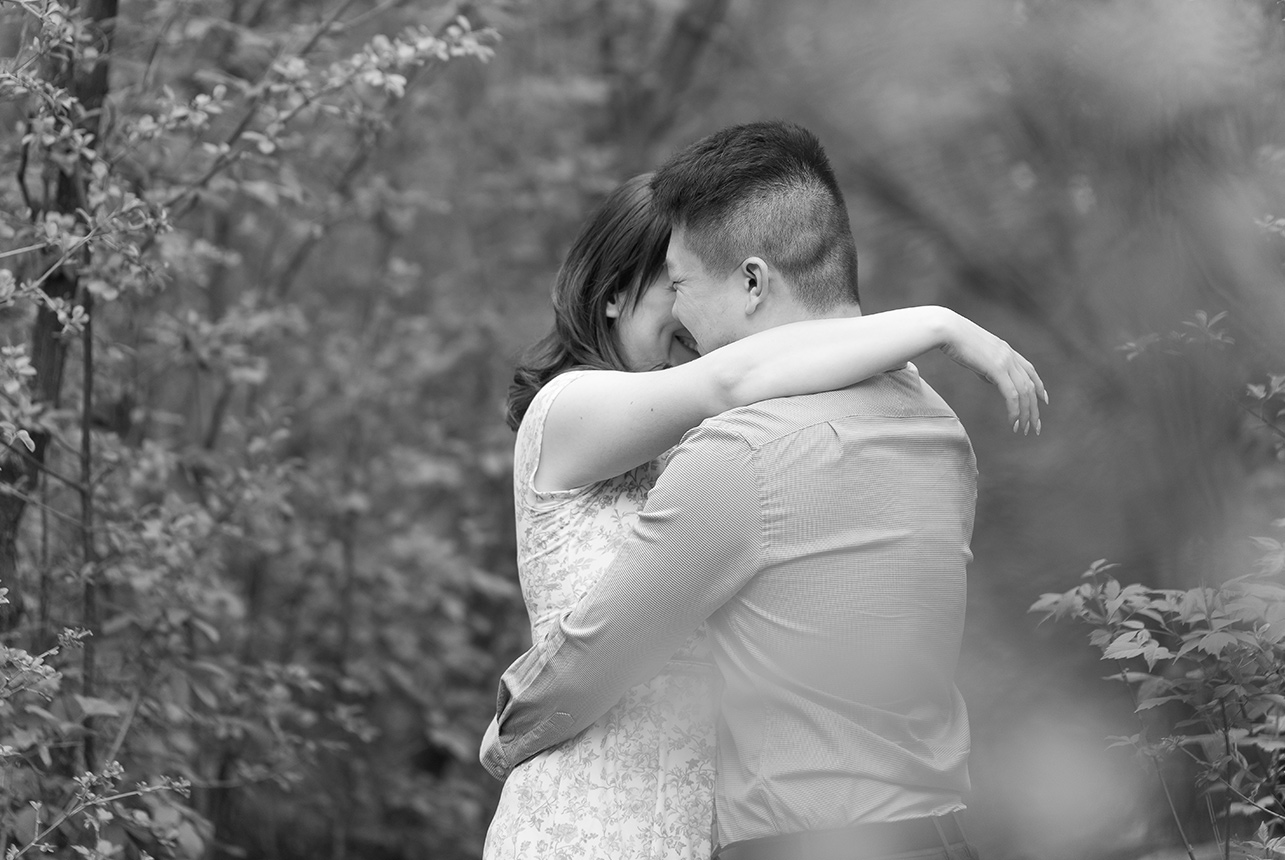 romantic hug forest black white photo Couple sharing a tender embrace with eyes closed in a black and white forest engagement portrait