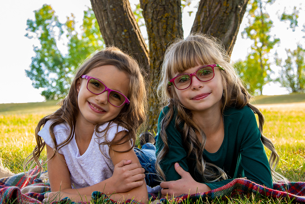 Two sisters lying on blanket in fall light at Centennial Park