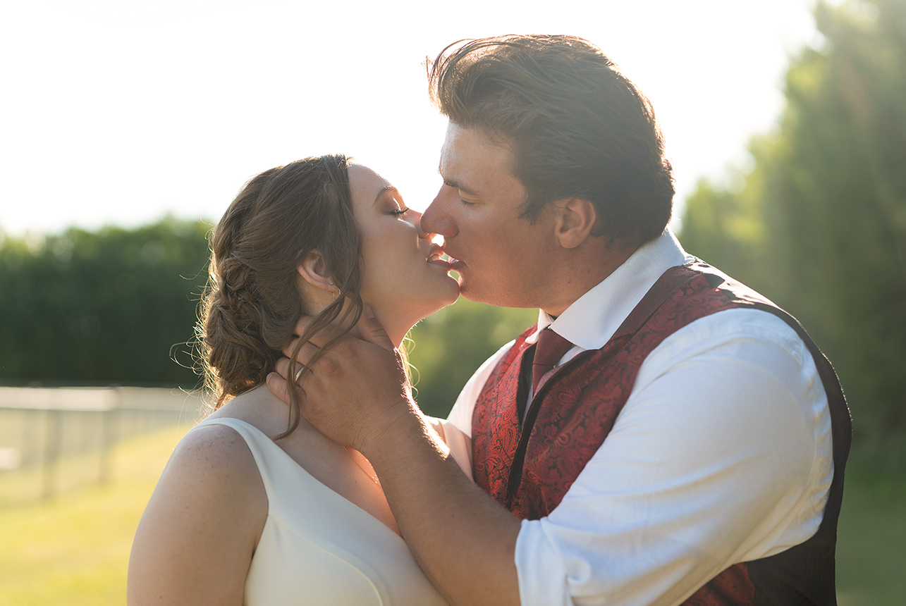 Bride and groom share a kiss in warm evening light