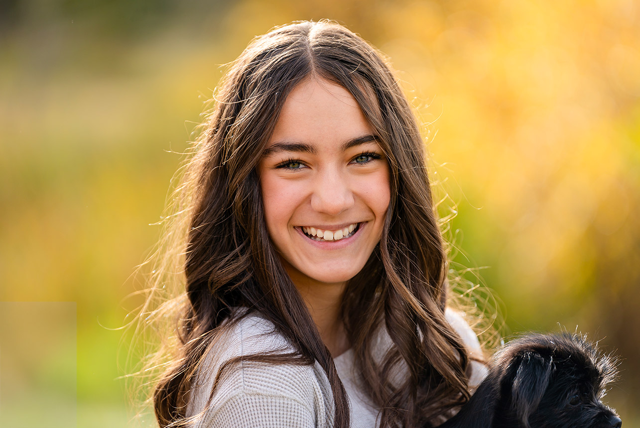 Smiling teen girl holding puppy at golden hour in Sherwood Park
