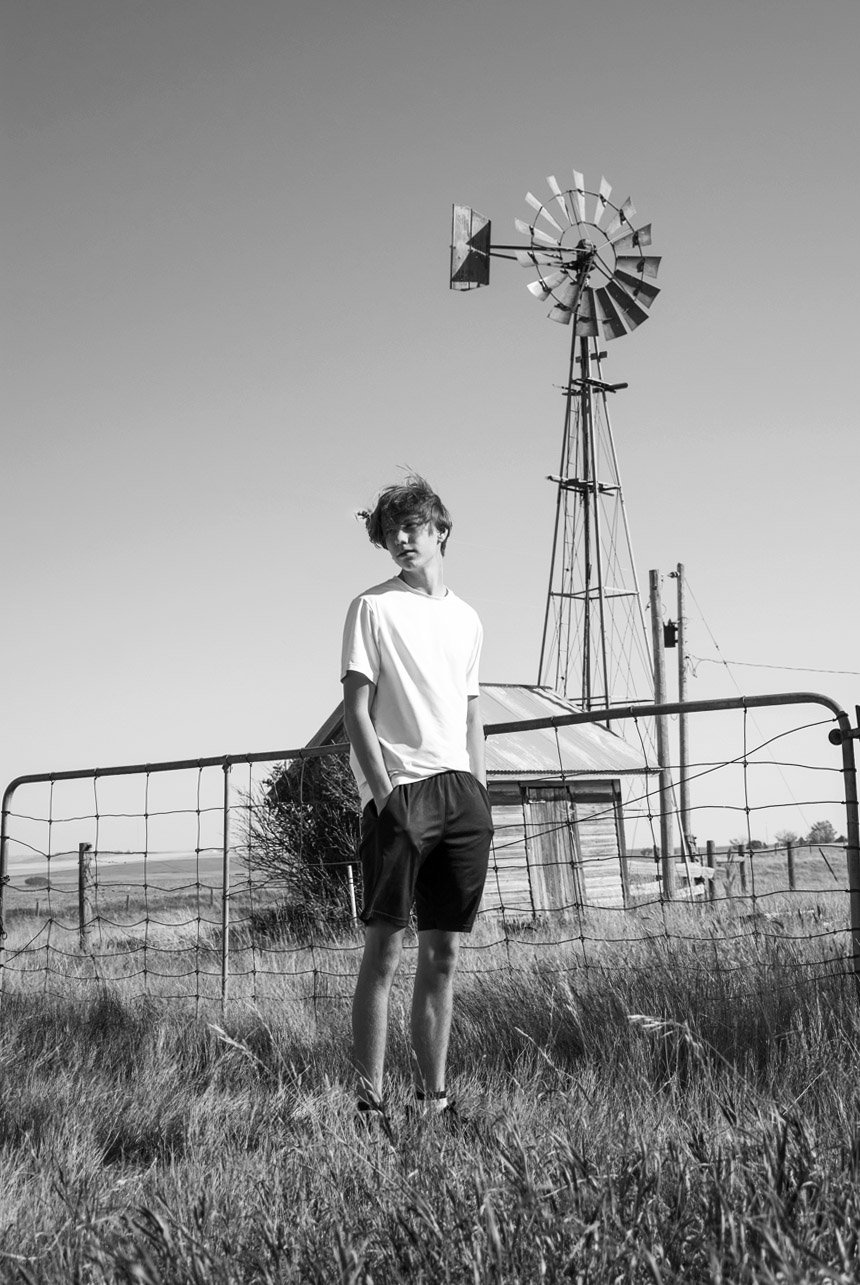 Teen standing near a vintage windmill at a historic farm near Vulcan, Alberta