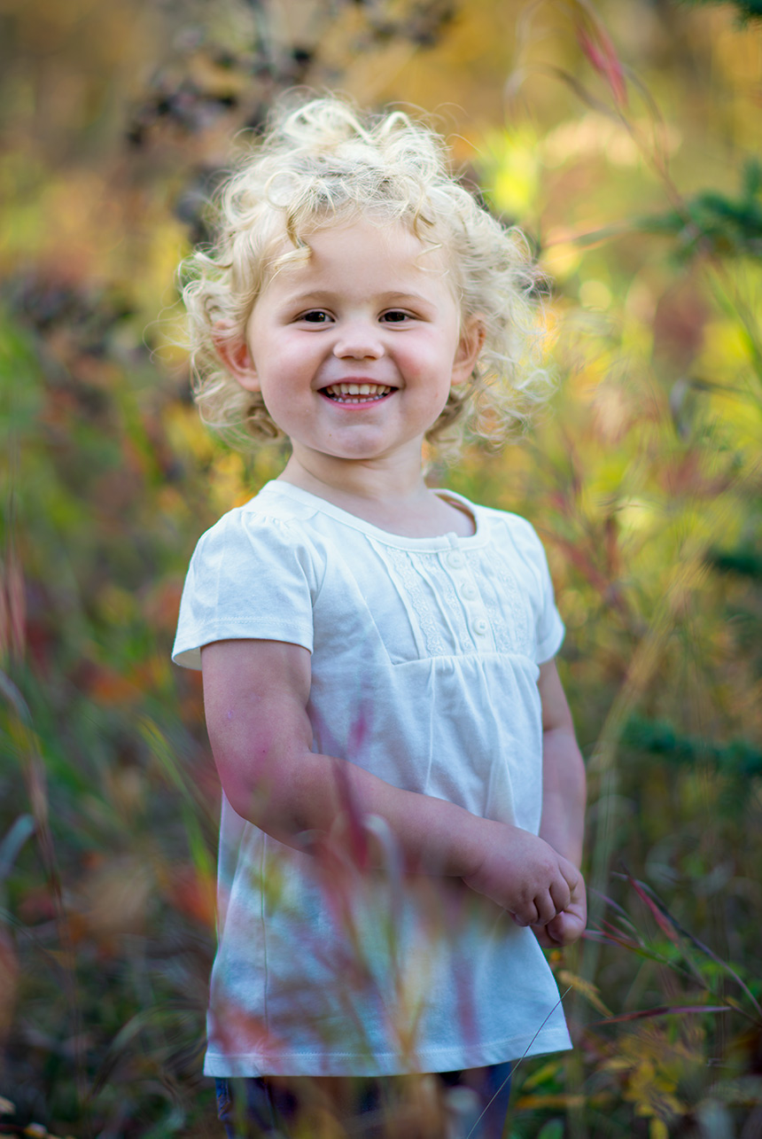 Smiling toddler with curly blonde hair in wild field at Mactaggart Sanctuary