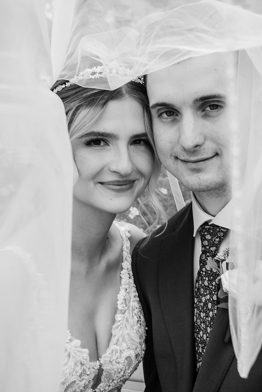 Bride and groom share an intimate black‑and‑white portrait beneath the bride’s veil during their Edmonton wedding