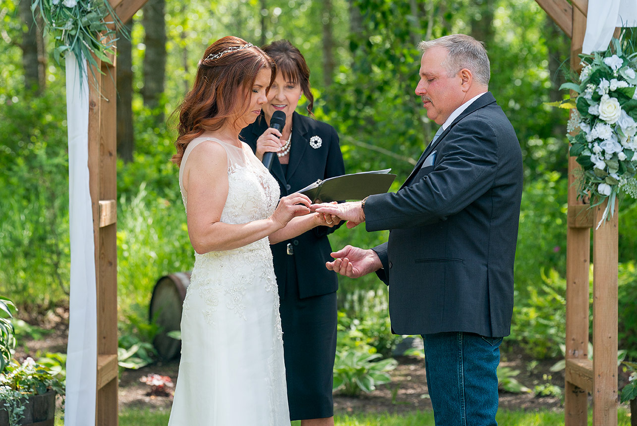 Bride places wedding ring on groom during outdoor ceremony