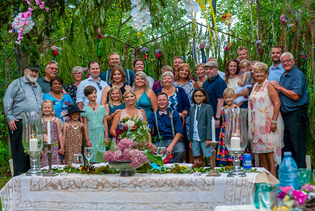 Group photo with bride and groom at outdoor forest wedding reception