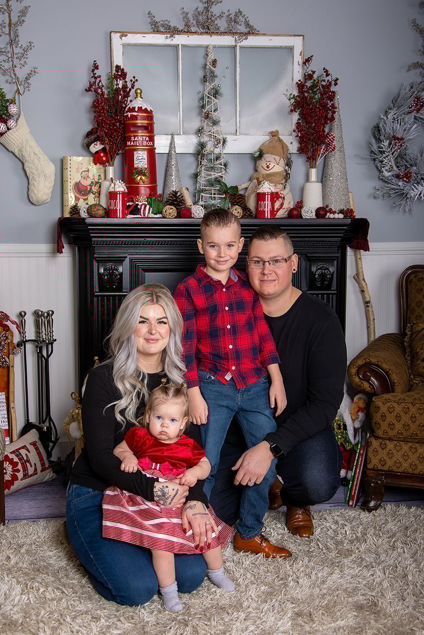 Young family huddled closely together on the floor in a festive Christmas room, surrounded by holiday decorations